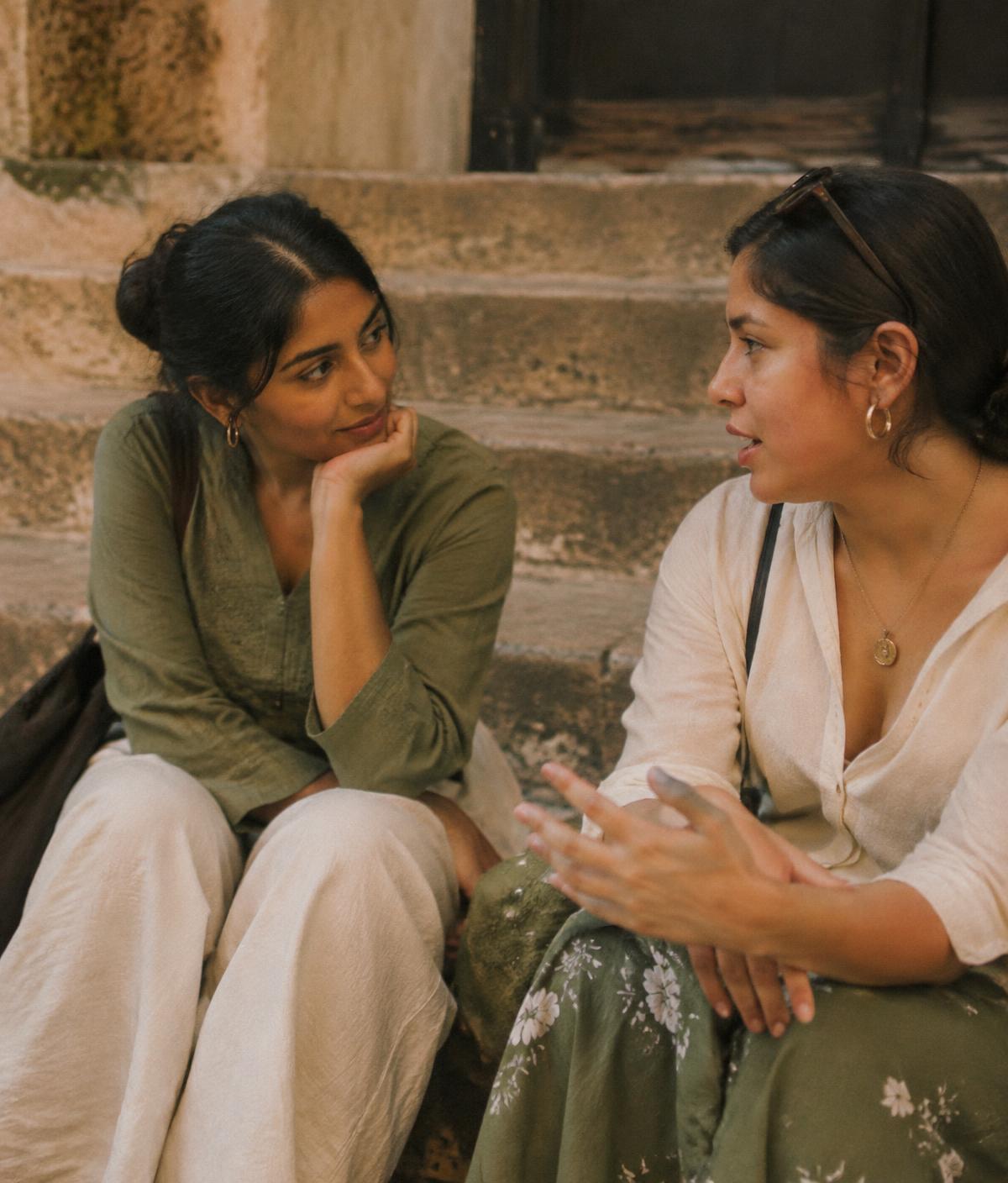 Two friends sitting on stone steps, one listening closely to the other